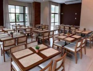 a dining room with tables and chairs and windows at Flat Rio Centro, 1km do Rio centro 3km da Jeunesse Arena Parque Olímpico em frente ao Projac e a poucos minutos da Praia da Barra in Rio de Janeiro