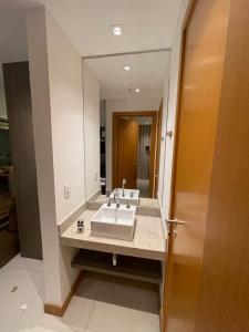 uma casa de banho com um lavatório e um espelho grande em Flat Hotel Samba Barra Jeunesse Arena Projac Rio Centro no Rio de Janeiro