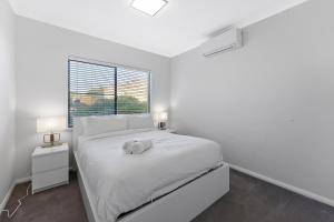 Un dormitorio blanco con una cama con un animal de peluche encima. en Modern Scarborough Townhouse, en Perth