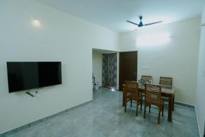 ein Esszimmer mit einem Tisch und Stühlen sowie einem Flachbild-TV in der Unterkunft Live Inn JP Nagar in Tiruchchirāppalli