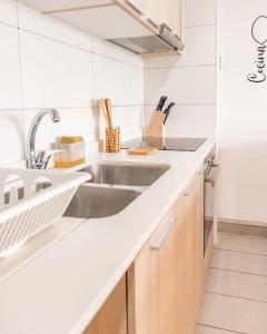 a white kitchen with a sink and a counter at Estancia Perfecta, Te esperamos! in Santiago