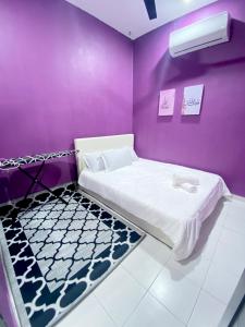 a room with a bed in a purple wall at AISY HOMESTAY - Rumah 2,3 in Kampong Tanjong Karang