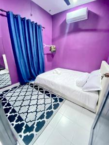 a bedroom with a bed and a purple wall at AISY HOMESTAY - Rumah 2 atau 3 in Kampong Tanjong Karang