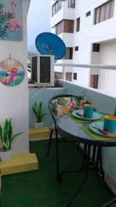 a table and chairs with cups and plates on a balcony at Apartamento con piscina cerca al mar Amoblado Rodadero Sur in Gaira