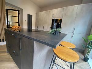 a kitchen with a counter and two stools at Stunning Town Center Cottage with hot tub in Morpeth