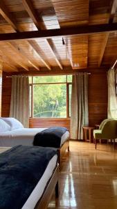 a bedroom with two beds and a large window at Zafiro Boutique Hotel in Mindo