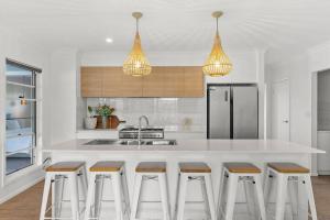 a kitchen with a white counter and bar stools at Blue Tide in Lennox Head
