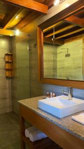 ein Bad mit einem Waschbecken, einem Spiegel und einer Dusche in der Unterkunft Zafiro Boutique Hotel in Mindo