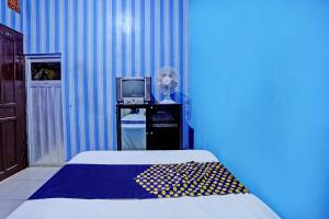 Cette chambre bleue comprend un lit et une télévision. dans l'établissement SPOT ON 92673 Gang Songo Syariah Homestay, à Banyuwangi