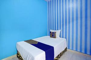 Ce lit se trouve dans un dortoir doté d'un mur bleu. dans l'établissement SPOT ON 92673 Gang Songo Syariah Homestay, à Banyuwangi