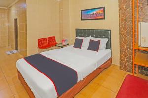 a bedroom with a large bed and a red chair at Super OYO Capital O 92676 Hotel Sion Holiday in South Tangerang