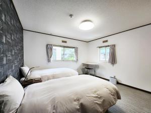 白馬的住宿－Hakuba Echoland Cottage，配有2张床的白色墙壁和窗户客房