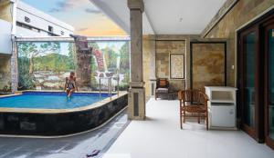 una mujer parada en una piscina en una habitación con un mural en AERO氧程巴厘岛潜水度假酒店, en Tulamben