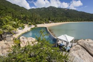 a swimming pool next to a beach with mountains at L'Alya Ninh Van Bay in Ninh Van Bay