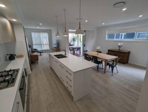 cocina y sala de estar con mesa y comedor en Bateau Bay Retreat, en Bateau Bay