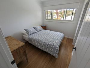 Bateau Bay Retreat في باتو باي: غرفة نوم صغيرة بها سرير ونافذة