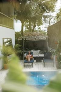 a man sitting on a chair next to a pool at Pousada Bem Te Vi Trancoso in Trancoso