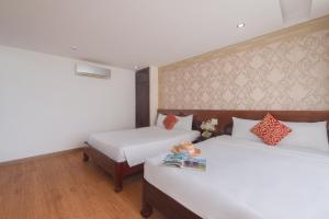 2 bedden in een hotelkamer met witte lakens bij LE SOLEIL HOTEL managed by NEST Group in Nha Trang