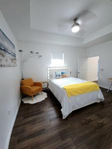a bedroom with a bed with a yellow blanket and a chair at Blue life in Lehigh Acres