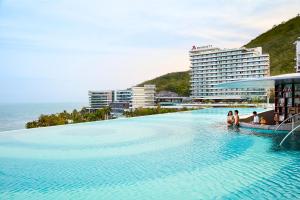 a large swimming pool with people sitting on it next to the ocean at The Shanhaitian Resort Sanya, Autograph Collection in Sanya