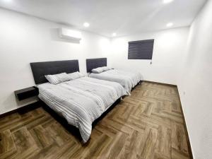 1 dormitorio con 2 camas y suelo de madera en Departamento Pitagoras No 3 en Ciudad Juárez