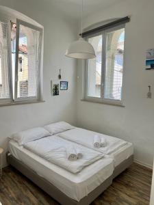 a white bed in a room with windows at OLD COURT KOPER in Koper