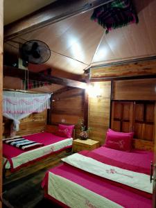 two beds in a room with wooden walls at Linh Homestay and motorbikes rent in Ha Giang