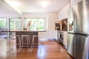 a kitchen with a stainless steel refrigerator and a wooden floor at Mid-Century Modern Retro Beach House in Caloundra