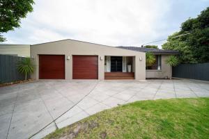 a house with two garage doors and a driveway at Spacious 3Bd n Pool family holiday home TF2223 in Frankston