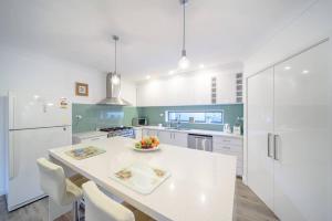 a white kitchen with a table and a bowl of fruit at Spacious 3Bd n Pool family holiday home TF2223 in Frankston