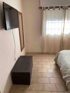 1 dormitorio con 1 cama y TV en la pared en Villegas Centro en Coronel Suárez