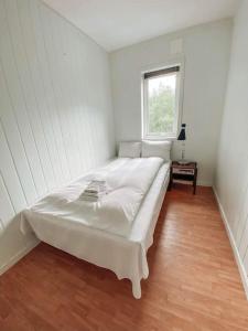a white bedroom with a bed in a room with a window at Trolltunga Sleep in Tveit