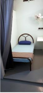 a small bed in a room with a curtain at Langkawi-Village Mix Dormitory in Pantai Cenang