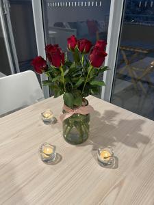 een vaas van rozen met kaarsen op tafel bij One-bedroom Apartment in heart of the City in Canberra