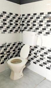 a bathroom with a toilet in a checkered wall at Misty Mountains Holiday Homes in Vattavada