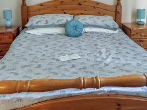 a bed with a wooden frame and a blue pillow on it at Park Lodge in Strachan