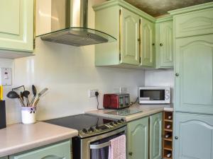 a kitchen with green cabinets and a stove top oven at Glen Nevis Cottage in Port Elphinstone