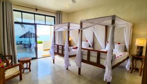 two beds in a bedroom with a view of the ocean at The Zanzibari in Nungwi