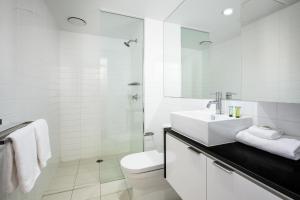 a white toilet sitting next to a white sink in a bathroom at Code Apartments in Brisbane