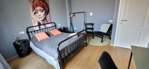 a bedroom with a bed and a painting of a woman at Bij Sarah in Leopoldsburg