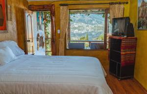 1 dormitorio con 1 cama, TV y ventana en Campo Lago Hospedaje, en Otavalo