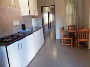 uma cozinha com armários brancos, uma mesa e uma sala de jantar em Lux contractors accommodation em Bronkhorstspruit