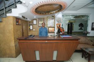 a man standing behind a bar in a room at Hotel Silver Arc - Karol Bagh New Delhi in New Delhi