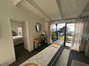 a bedroom with a bed and a desk with a mirror at Private Water Front House in Whangaparaoa