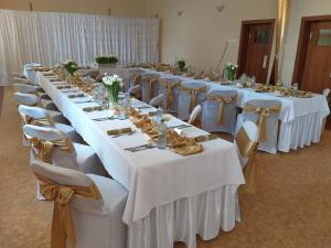 a row of tables with white table cloths and chairs at Penzion Bruder in Mojmírovce