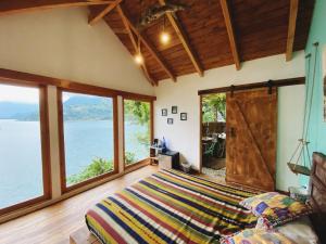 a bedroom with a large bed and large windows at Baba Yaga Atitlan in San Marcos La Laguna