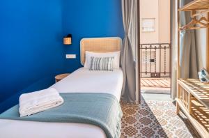 een bed in een kamer met een blauwe muur bij Caliu Apartments Barcelona in Hospitalet de Llobregat