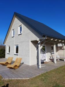a house with a roof and two chairs on a deck at Ciche Wydmy in Sasino
