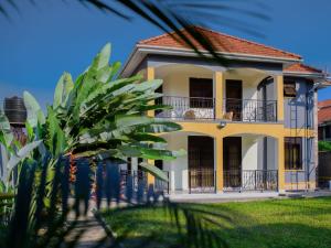 a yellow house with a balcony and a palm tree at K-Cube Villas in Kampala