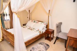 a bedroom with a canopy bed and a chair at K-Cube Villas in Kampala